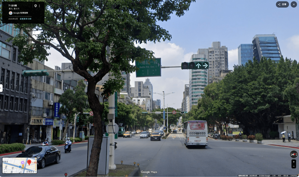 街道場景,包含交通信號燈和行駛中的巴士,周圍有商業建築和樹木。