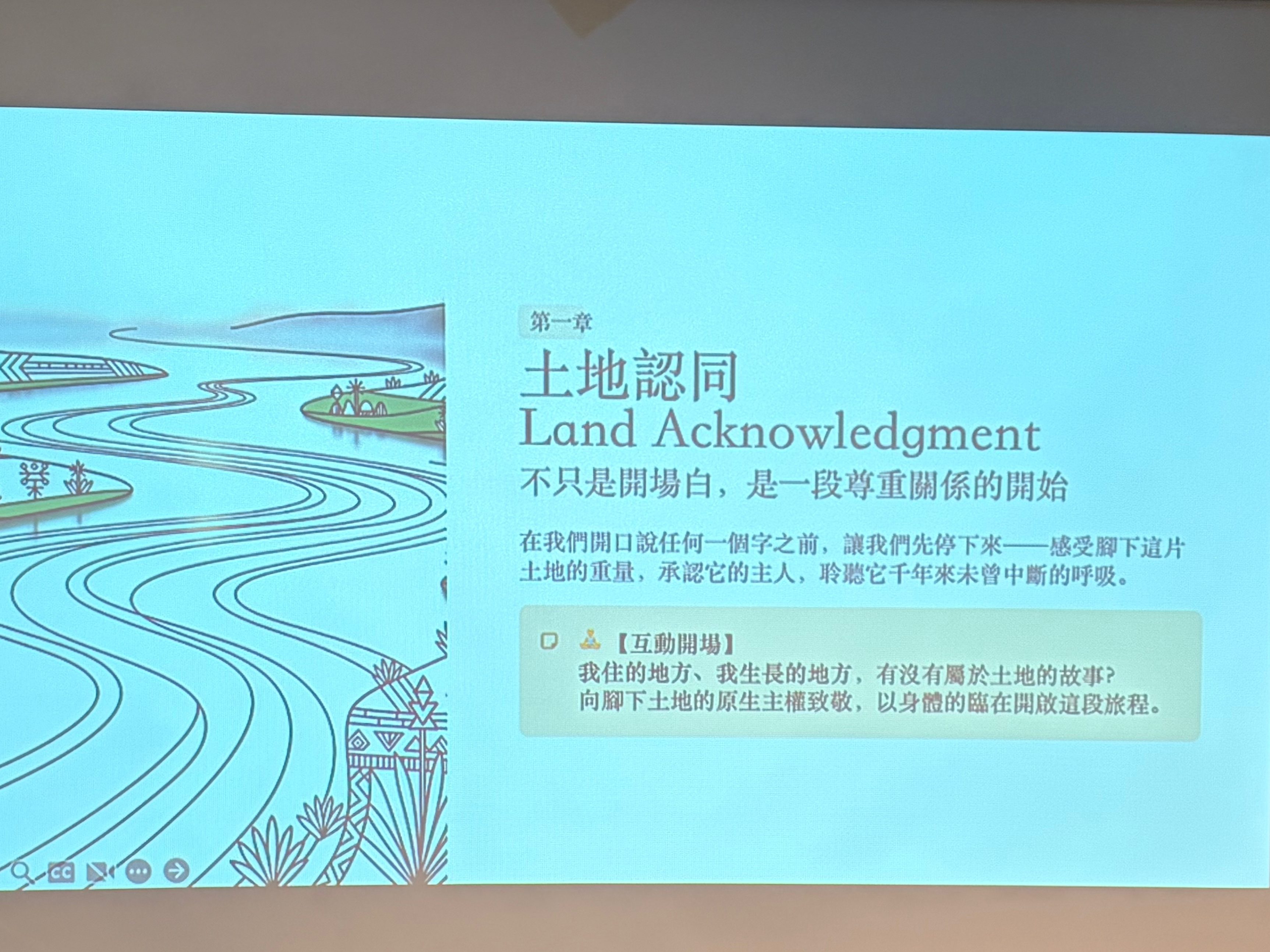 一位年輕女性坐在桌子前，手持麥克風，面向投影螢幕。螢幕上顯示有關土地認同的內容，包括中文與英文的文字。背景是一面磚牆，顯示出一種創意和文藝的環境。