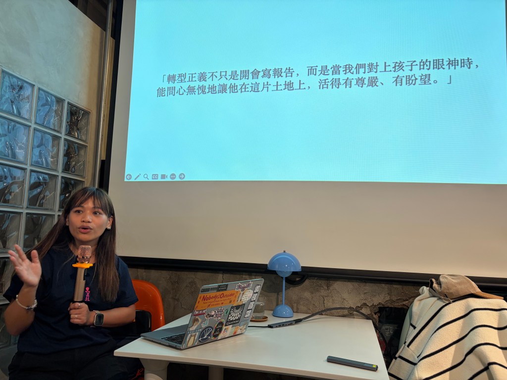 一位女性正在一個工作坊中發言，背景投影呈現文本，討論有關教育和孩子的主題。