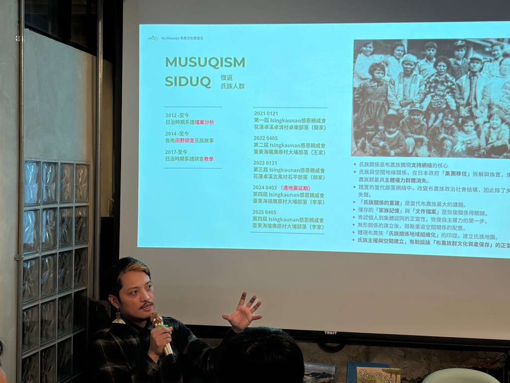 一位正在演講的男性,手持麥克風,背景是一個顯示的幻燈片,上面有關於復甦族群的資訊和歷史照片。
